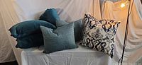 Stack of four teal ribbed pillows, teal woven pillow, patterned damask pillow