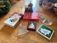 All items arranged: bell dish, wood village house, three boxed dishes, boxed rectangular/oval dish, clear oval tray partially visible