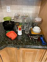 Countertop view of mixed glassware, bowls, bar tools and serving pieces