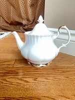 Side view of teapot showing body shape, handle and gold trim