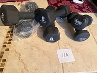 Four 8 lb hex dumbbells and two 5 lb neoprene dumbbells displayed on floor