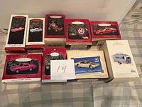 Ten Hallmark Keepsake car ornament boxes arranged in two rows with paper showing number 14