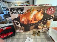 Boxed Quantum2 turkey roaster with brass figures and portion of lazy susan visible