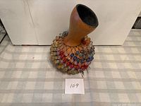 Full view of shekere standing upright showing gourd neck and beaded netting