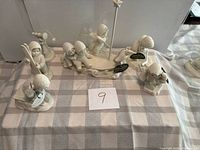 Overall view of six Snowbabies figurines on checked cloth