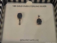 Close view of both earrings in box showing gemstones and metal