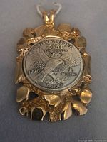 Pendant front showing coin details and gold-plated frame