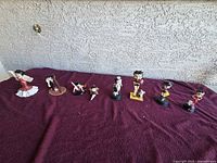 All eight Betty Boop figurines lined on burgundy cloth