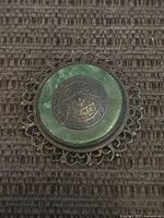 Front view of round sterling brooch showing green stone and Aztec calendar medallion