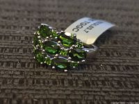 Top view of sterling silver ring showing green gemstone cluster and attached tag