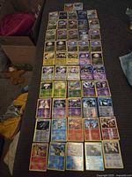 Overall view of approximately 60 holographic Pokémon cards laid out in grid