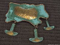 Front view showing hammered brass centre, green enamel surface, three dangling plates
