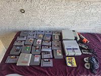 Overall lot with consoles, controllers, light gun, cables and roughly thirty cartridges displayed on towel