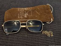 Full view of sunglasses, suede pouch, and chain