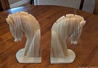 Front view of both alabaster horse head bookends on wooden surface