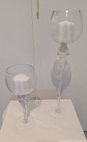 Both clear glass stem candle holders with candles shown for scale