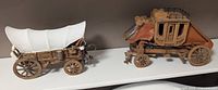 Side-by-side view of wooden stagecoach and covered wagon models showing overall design and condition