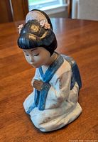 Front view of porcelain figurine kneeling on wood surface