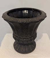 Front view of black metal urn planter showing flared rim and pedestal base
