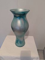 Full view of aquamarine iridescent glass vase on white surface