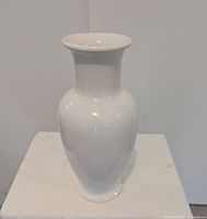 Front view of glossy white ceramic vase on stand