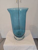 Front view of tall aquamarine glass vase with beads inside