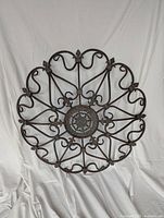 Full view of brown metal round wall decor with scrollwork