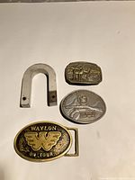 All three belt buckles and U-shaped magnet laid out on white background