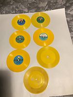 Seven yellow 6-inch singles displayed label-side up