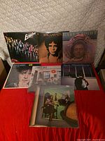 All seven album covers laid out on red surface