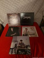 All five album covers laid out on red surface