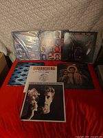 All seven record sleeves laid out on red surface