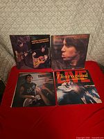 Four album covers displayed on red surface