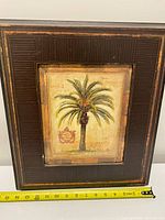 Full view of framed palm tree print with measuring tape for scale