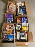 Six open boxes filled with varied books on floor