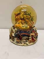 Front view of entire snow globe showing Santa and animals, decorative base