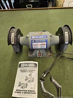 Front view of King Canada 6" bench grinder with manual, shields and power cord visible