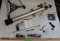 All components laid out including tube, tripod legs, eyepieces, manual, accessories