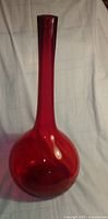 Full view of tall red glass vase showing overall shape