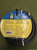 Coiled black rubber air hose with Power Fist retail label showing specifications