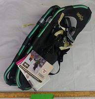 Folded pair of green and black Tubbs Vertex snowshoes showing bindings and tags