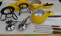 Complete fondue set laid out showing pot, lid, stands, trays, burners and forks