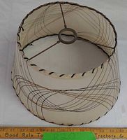 Overall view of cream fiberglass lampshade showing swirl pattern, laced trim and spider fitter