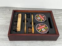 Open kit showing large brush, two dauber brushes and two polish tins in foam insert