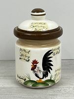 front view of ceramic canister showing rooster motif, brown rim and lid