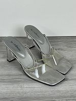 Oblique front view showing clear uppers, square toes, brand on insoles