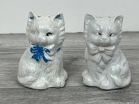 Front view of both ceramic cat shakers showing bows and paint wear