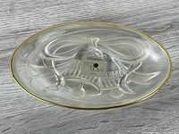 Top view of clear glass oval dish displaying bow motif and gold-tone rim