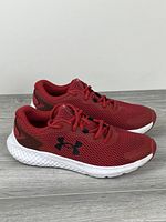 Lateral side view of both red Under Armour Charged sneakers