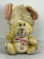 Front view of yellow Buckie Bear plush showing bow tie, belly buttons, ears, face